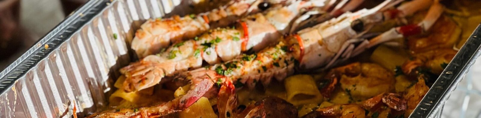 Tempting close-up of grilled seafood in a catering tray, perfect for buffet meals.